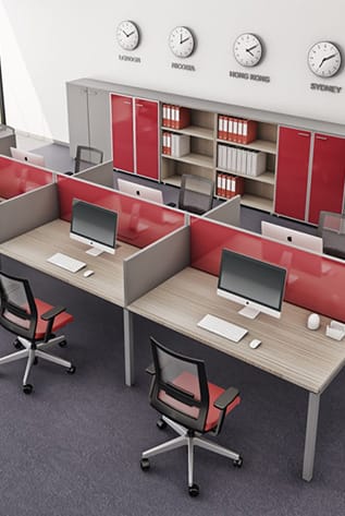 Office interior with low partition screens, desks, chairs, computers, and clocks displaying different time zones.