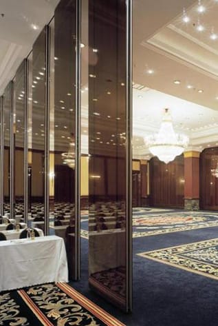 Movable walls dividing a large ballroom, reflecting the tables and chandelier.