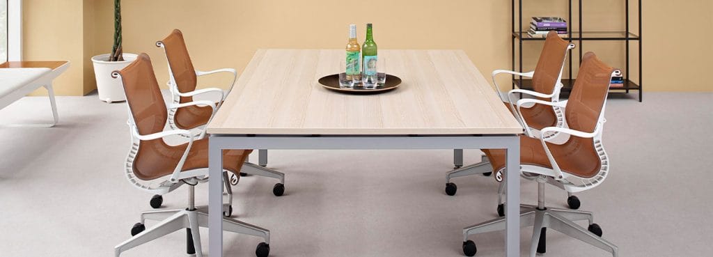 Light wood Sense Conference Table with metal frame and brown mesh chairs, office setting.
