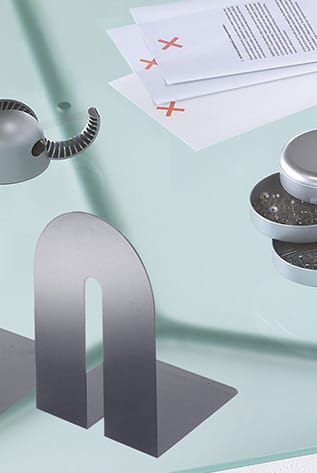 Modern desk sets. Metal bookends, stapler, and paper on a glass desk.