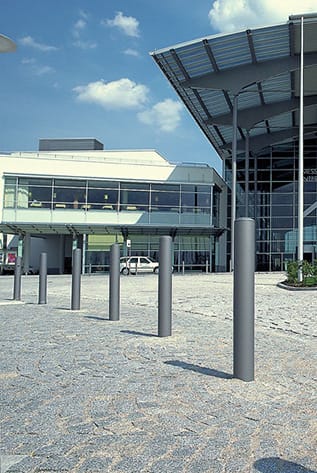 Modern street furniture: Sleek, gray bollards enhance urban space. Durable design for pedestrian safety and aesthetic appeal.