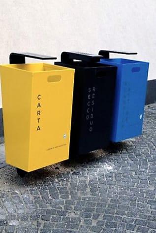 Modern street furniture: Yellow, black, and blue recycling bins with black handles.