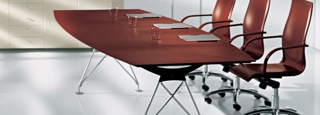 Consilium Conference Table with brown wood finish and modern metal legs, paired with leather office chairs.