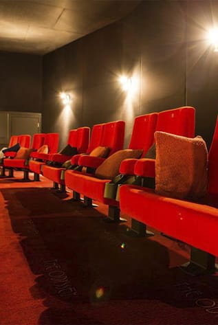 Red plush Cinema seating with lumbar support, cup holders, and reclining options for ultimate comfort.