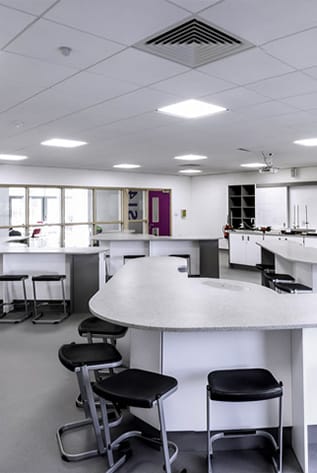 Bright, modern laboratory featuring durable, white Laboratory Furniture and black stools.