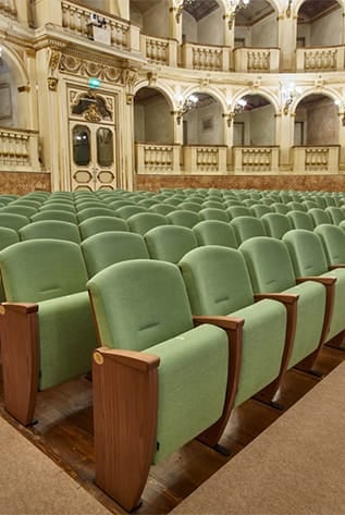 Elegant Theater seating with green upholstery and wood trim.