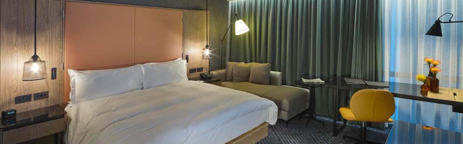 Elegant Hotels bedroom with a bed, sofa, desk, and chair. Hospitality furniture.