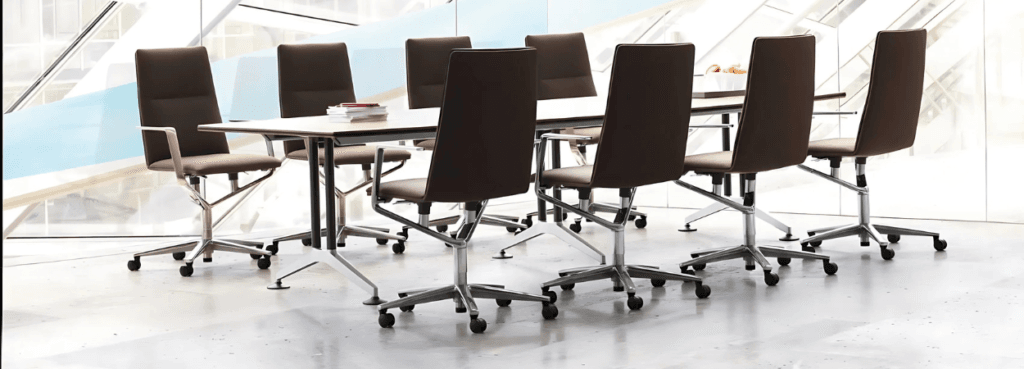 Τραπέζι Wilkhahn Logon Conference Table με καφέ καρέκλες, μεταλλικά πόδια και ανοιχτόχρωμη επιφάνεια.