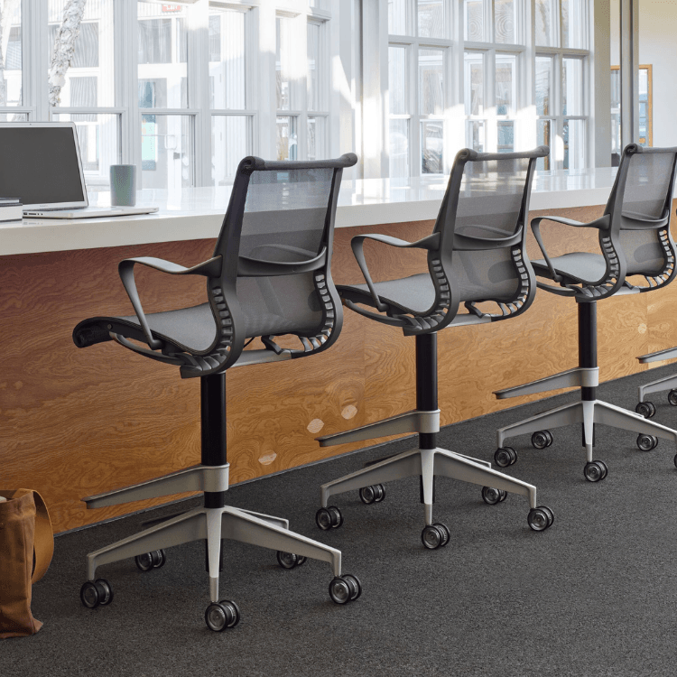 Πλάγια όψη γκρι σκαμπό Setu της Herman Miller με διχτυωτή πλάτη και κάθισμα, σε τροχούς.