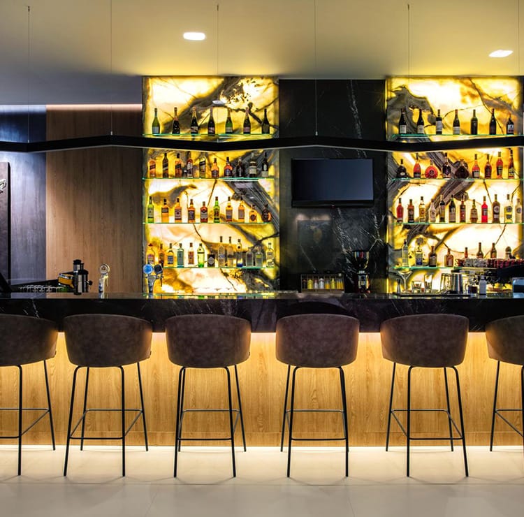 Stylish Bars with marble counter, leather stools, and backlit liquor shelves.