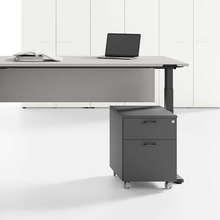 Modern gray UP desk with file cabinet, laptop, and book in a bright office space.