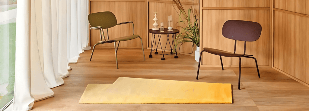 Σύγχρονο εσωτερικό με πολυθρόνα New School Lounge από κόντρα πλακέ σε πράσινο και καφέ, και κίτρινο χαλί.