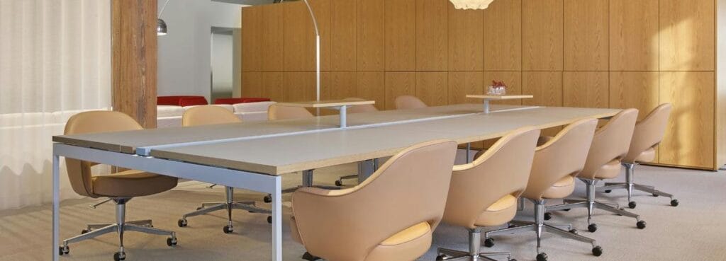 Saarinen Executive Chair της Knoll σε ταμπά δέρμα, δίπλα σε μακρύ τραπέζι συσκέψεων σε σύγχρονο χώρο γραφείου.