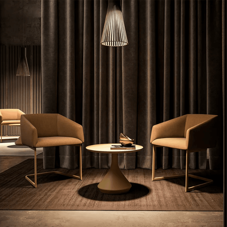 Σύγχρονο τραπέζι Lamp. Στρογγυλό τραπέζι με βάση σε σχήμα φωτιστικού, καφέ καρέκλες και σκούρα κουρτίνα στο φόντο.