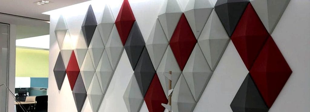 Ηχοαπορροφητικά πάνελ 3D Diamond Grid από κόκκινη, γκρι και λευκή τσόχα, με έντονο ανάγλυφο που θυμίζει κοπή πολύτιμου λίθου, σε τοίχο γραφείου.