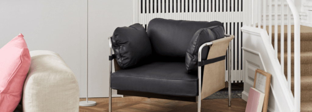 Μινιμαλιστική μαύρη δερμάτινη πολυθρόνα CAN 1 Seater με εμφανή χρωμιωμένο σκελετό και μπεζ πλαϊνά πάνελ, σε φωτεινό εσωτερικό κατοικίας.