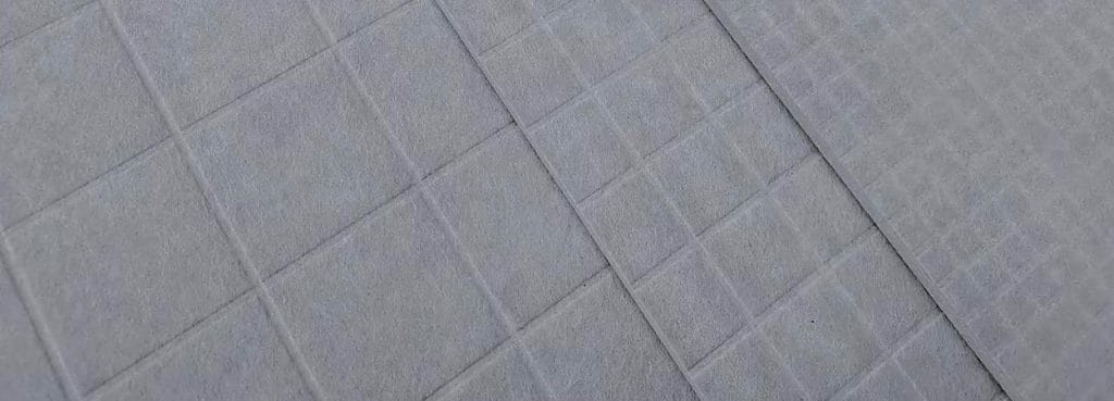 Κοντινό πλάνο γκρι ακουστικού πάνελ Grid από ανάγλυφη τσόχα PET με ακριβές ανάγλυφο τετραγωνικό κάνναβο.