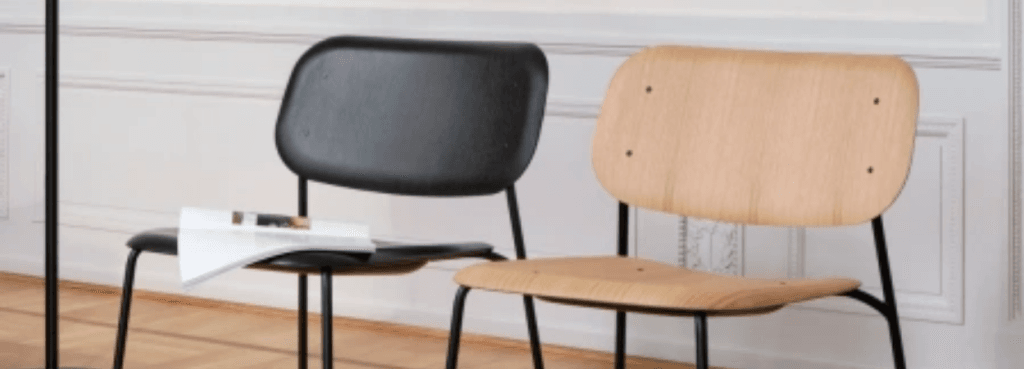 Αντίθεση μαύρου και δρυός στις καρέκλες Soft Edge 100, με καμπυλωτά καθίσματα από κόντρα πλακέ και λεπτούς μαύρους μεταλλικούς σκελετούς, σε ένα δωμάτιο.