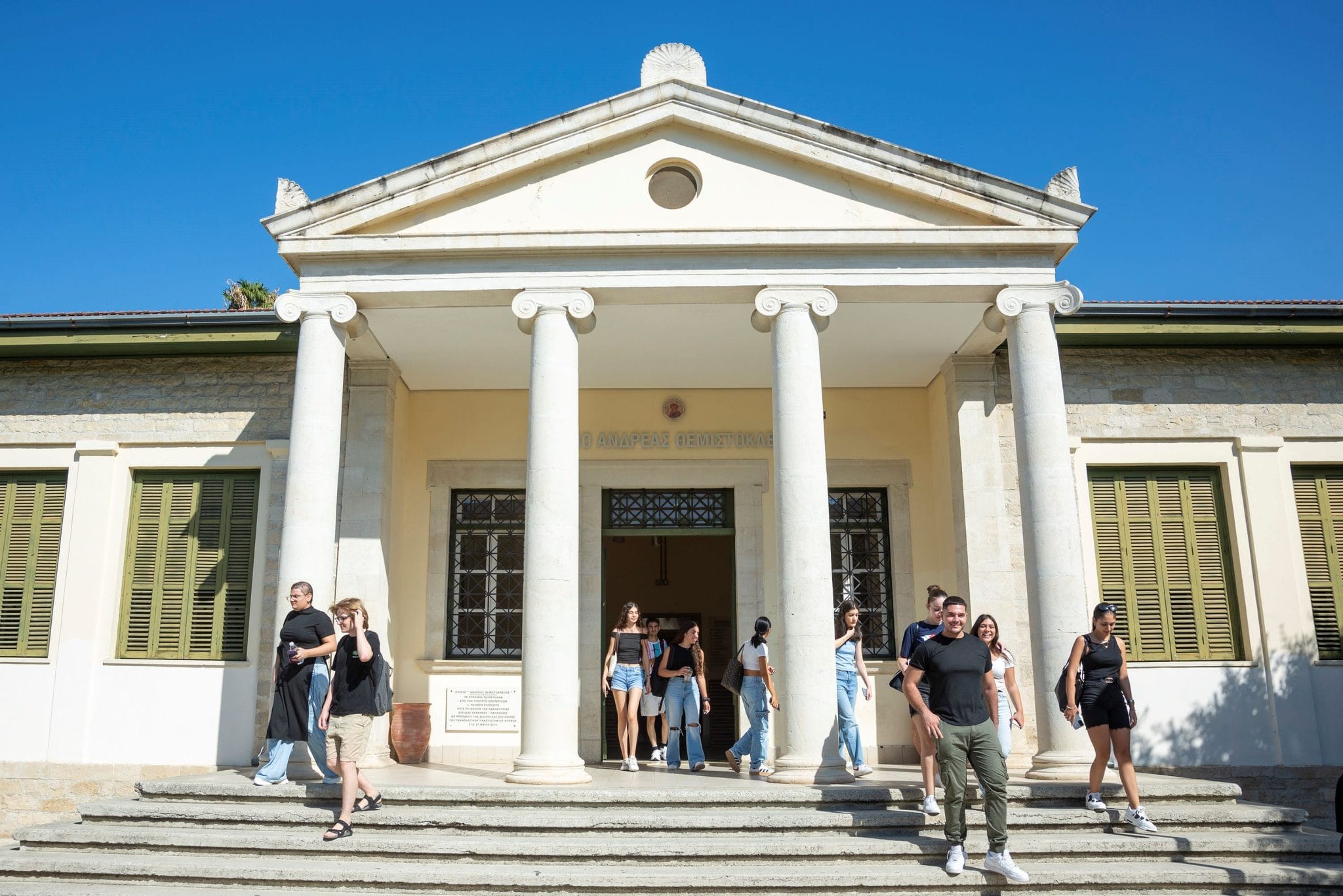Φοιτητές βγαίνουν από νεοκλασικό κτίριο του Τεχνολογικού Πανεπιστημίου Κύπρου, κάτω από αέτωμα που στηρίζεται σε λευκούς κίονες.